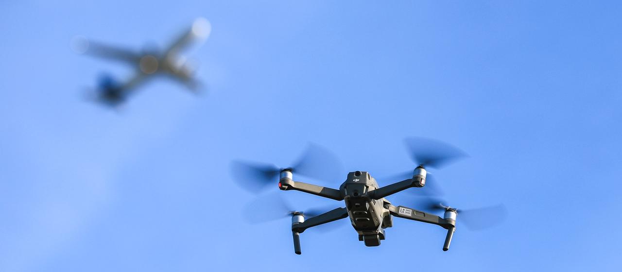 Eine Drohne fliegt vor einem startenden Flugzeug in der Nähe des Flughafens Leipzig/Halle.
