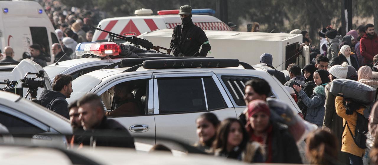 Ein Mitglied der Sicherheitskräfte steht Wache, während Einwohner aus dem kurdischen Viertel Ashrafieh in Aleppo (Syrien) fliehen.