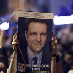 Jubelnde Anhänger von Nicusor Dan halten ein Wahlplakat hoch.