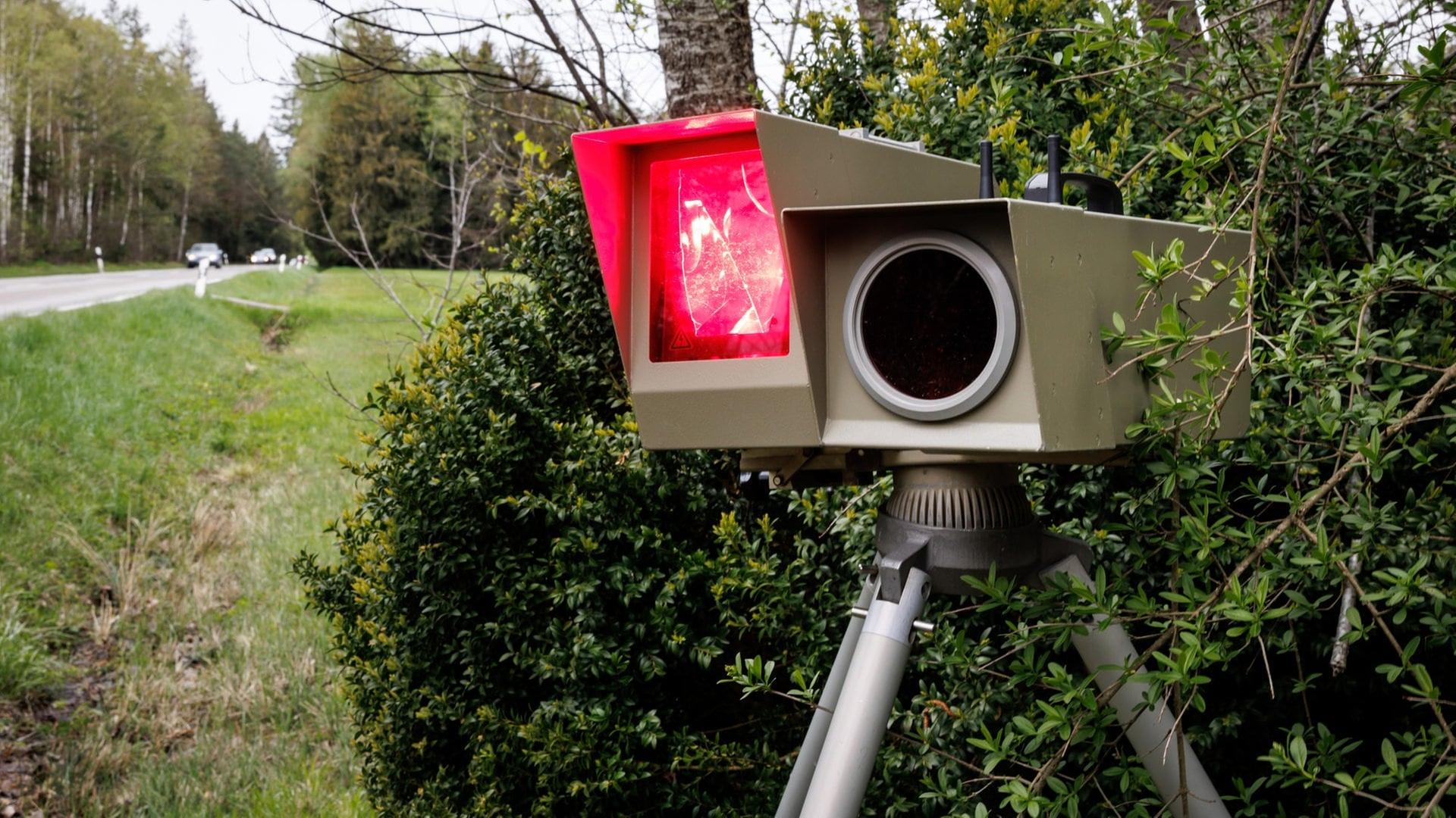 Ein mobiles Blitzgerät  zur Geschwindigkeitsüberwachung mit rot leuchtendem Blitzlicht steht am Straßenrand einer Landstraße. | dpa Bildfunk, picture alliance / dpa | Matthias Balk