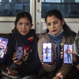 Frauen in Kathmandu halten Handys mit Fotos ihrer in der Ukraine kämpfenden Männer.