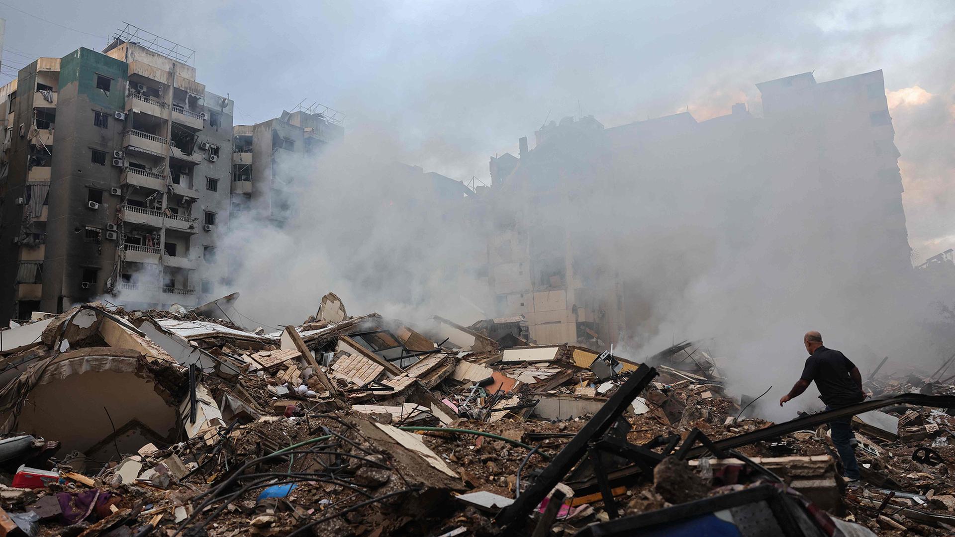 Ein Mann geht in Beirut über die Trümmer von Häusern.