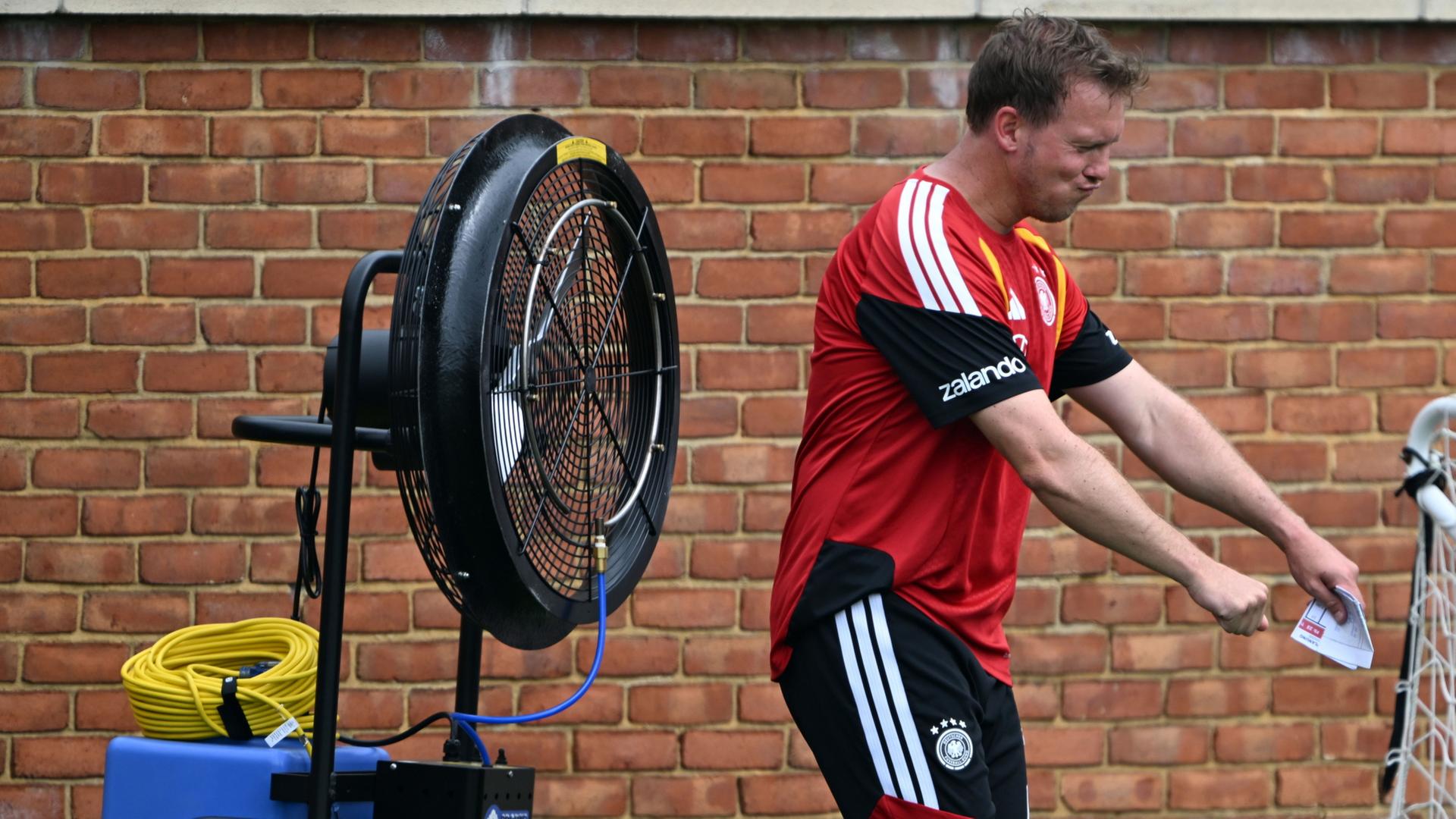 Julian Nagelsmann erfrischt sich vor einem Ventilator. | Federico Gambarini/dpa
