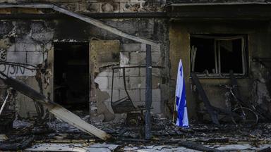 Eine israelische Fahne steht neben einem von der Hamas zerstörten Haus im Kibbuz Be'eri.