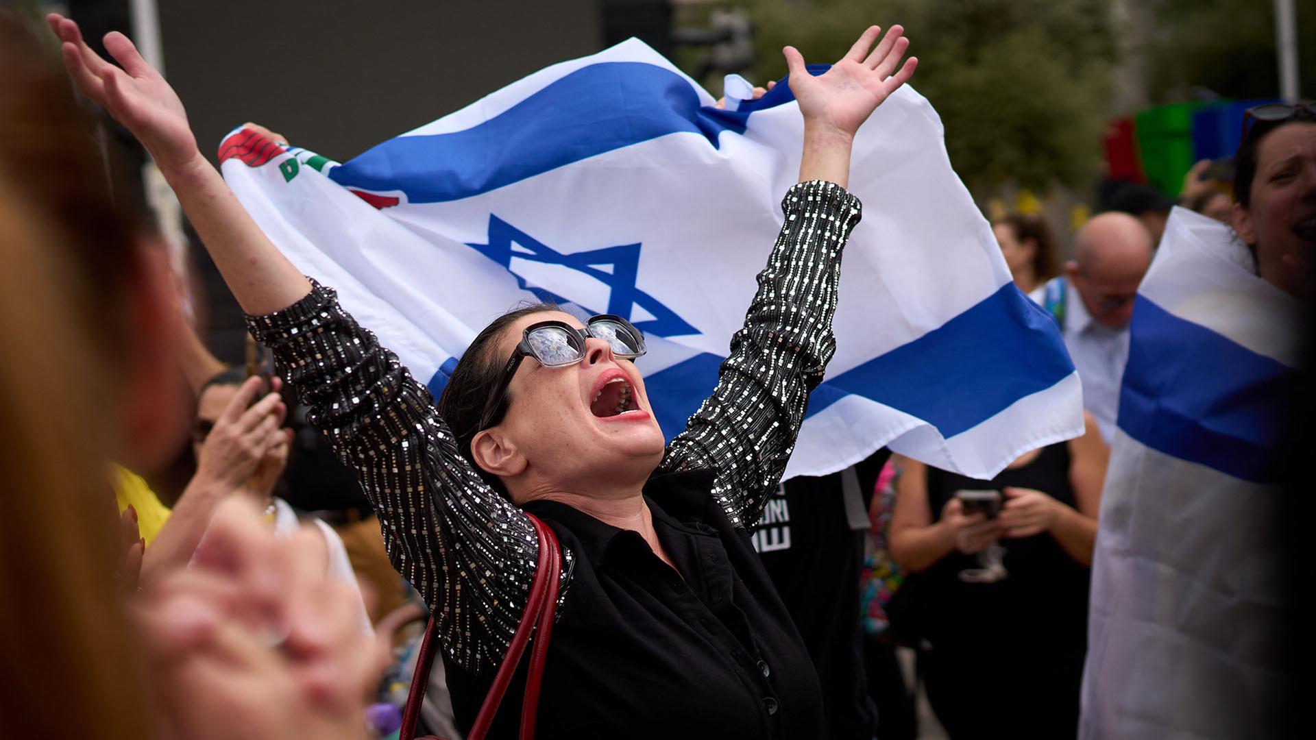 Eine Frau streckt die Arme in die Luft, neben ihr sind Menschen mit Israel Flaggen. | AP