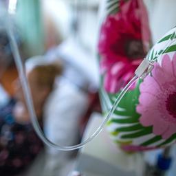 Ein Tropf an einem Stoffherz auf einer Station der Palliativ Medizin - im Hintergrund eine Patientin (unscharf)-