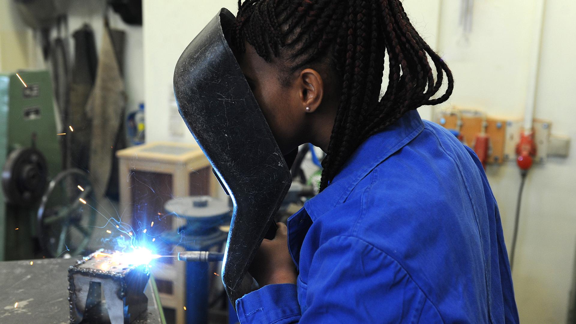 Eine Frau aus Guinea absolviert in der Metallwerkstatt der Allgemeinen Berufsschule in Bremen einen Kurs im E-Schweißen. | picture alliance/dpa