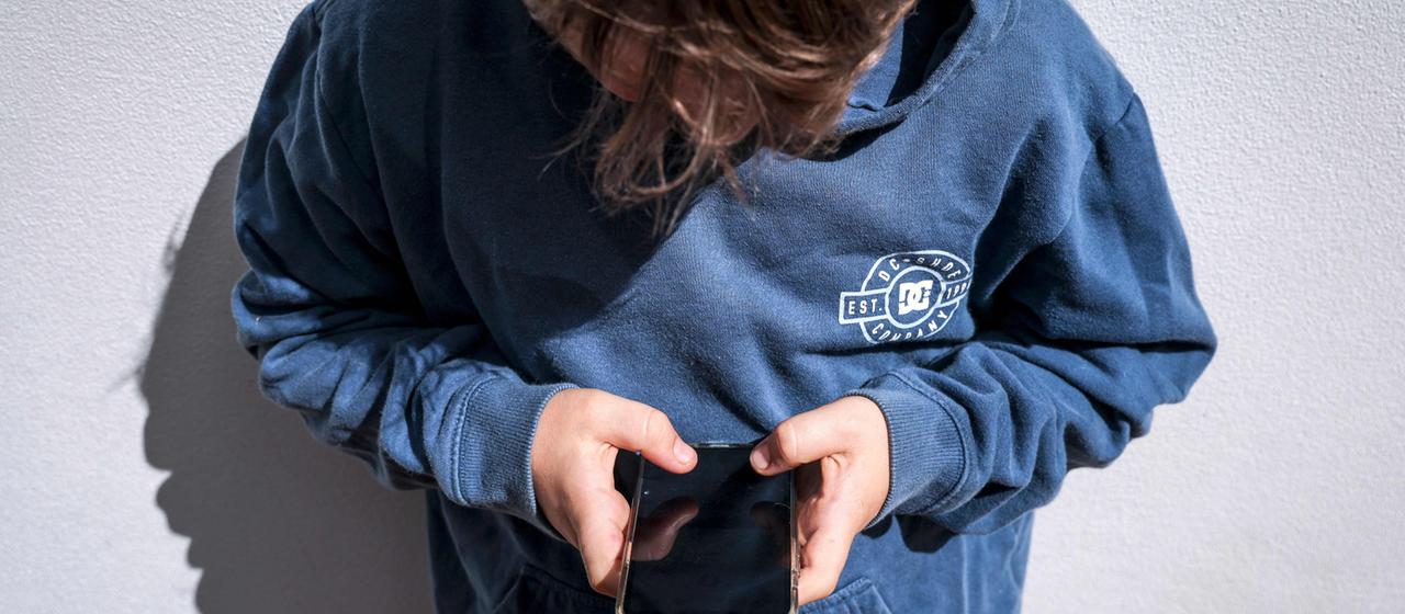 Ein Kind schaut auf ein Smartphone.
