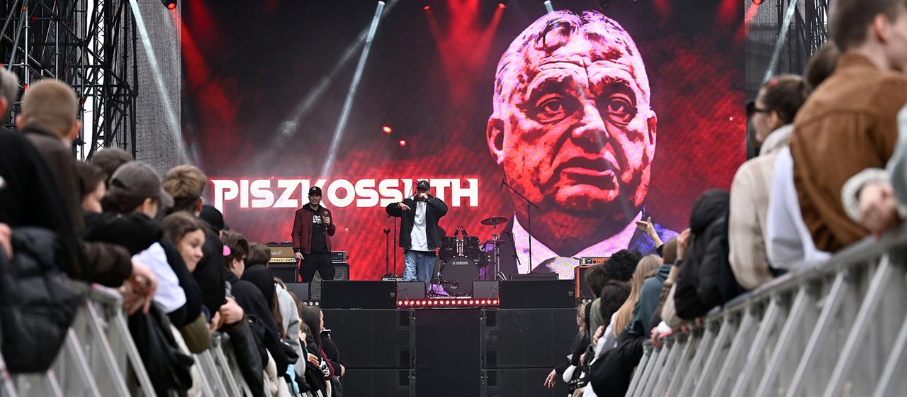 Eine Rap-Gruppe tritt auf einem Open-Air-Festival auf. Ein Backdrop zeigt eine Illustration Viktor Orbáns.