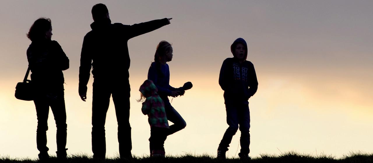 Unter dem abendlichen Wolkenhimmel geht eine Familie spazieren (Archivbild)