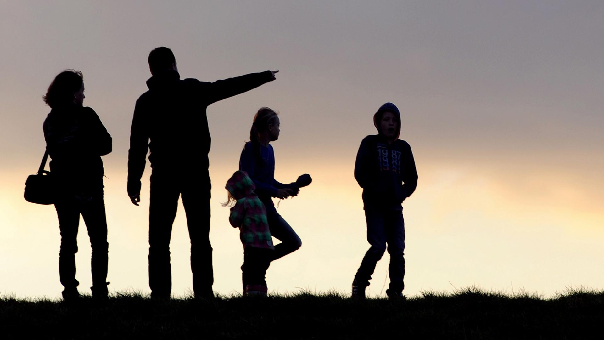 Unter dem abendlichen Wolkenhimmel geht eine Familie spazieren (Archivbild) | dpa
