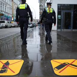 Eine Polizistin und ein Polizist gehen in Hamburg an den neuen Piktogrammen zum Glasflaschen- und Waffenverbot in der Talstraße unweit der Reeperbahn vorbei.