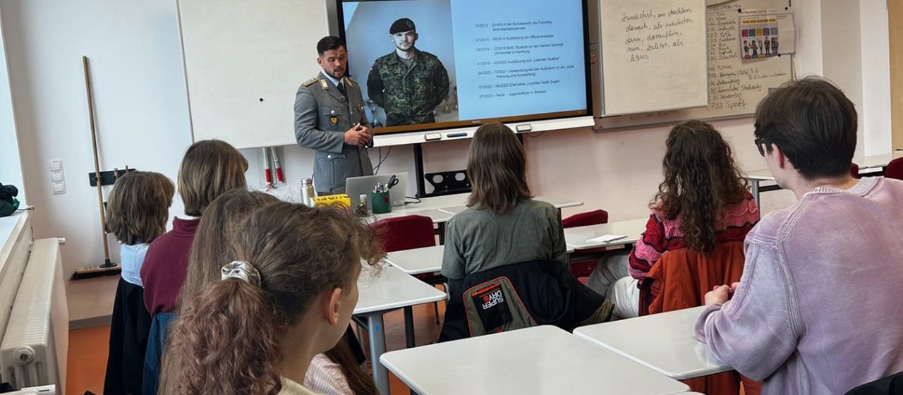 Eine Jugendoffizier der Bundeswehr hält einen Vortrag vor Schülern in einem Klassenzimmer.