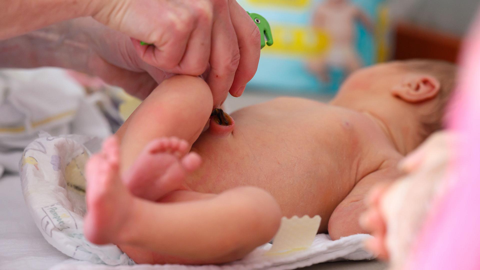 Eine Kinderkrankenschwester wickelt ein Neugeborenes auf einer Neugeborenenstation. | Hendrik Schmidt/dpa