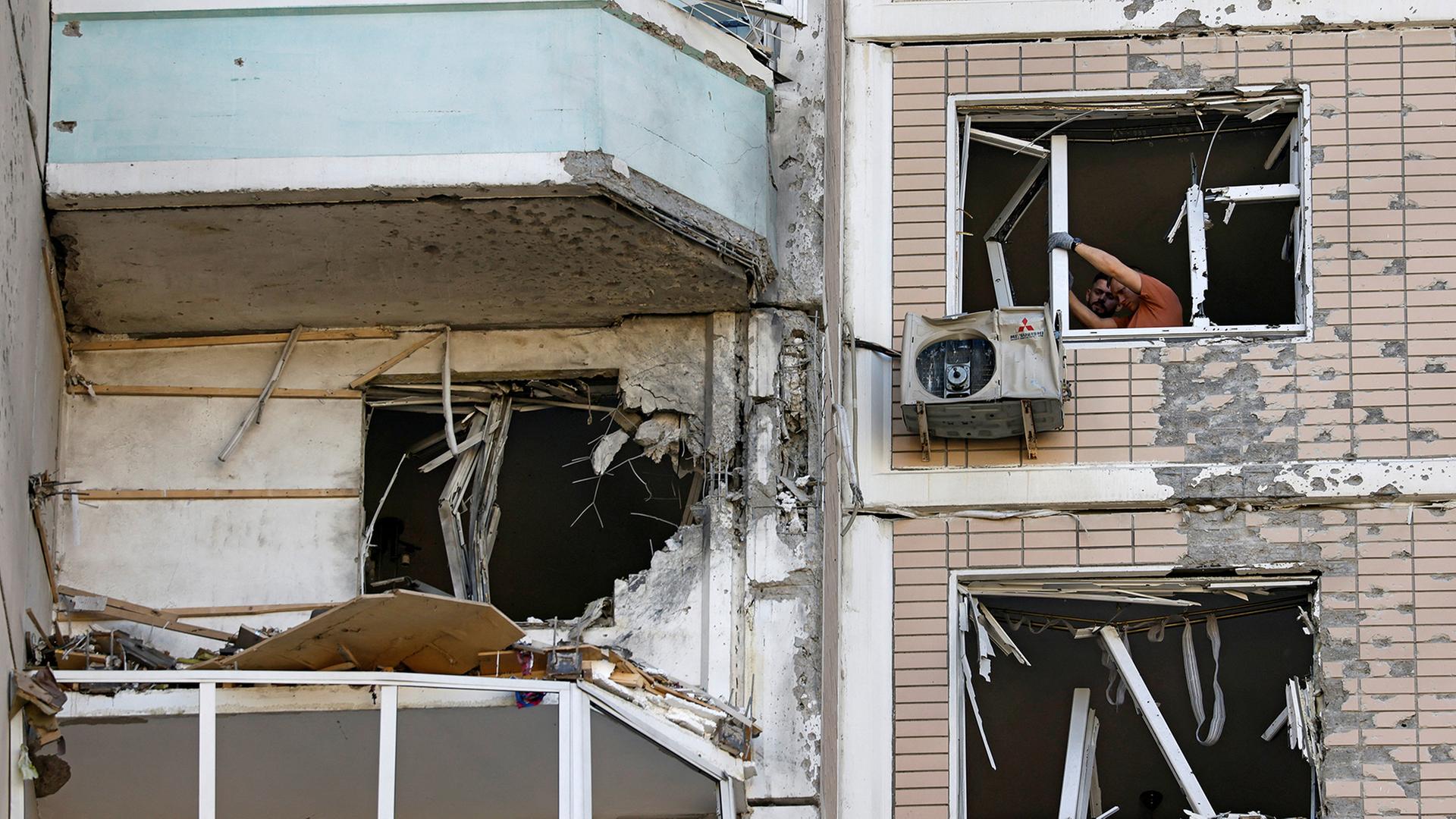 Männer stehen an zerstörten Fenstern in einem beschädigten Haus in der Region Moskau. | REUTERS