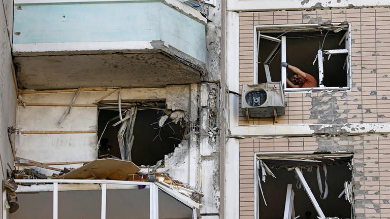 Männer stehen an zerstörten Fenstern in einem beschädigten Haus in der Region Moskau.
