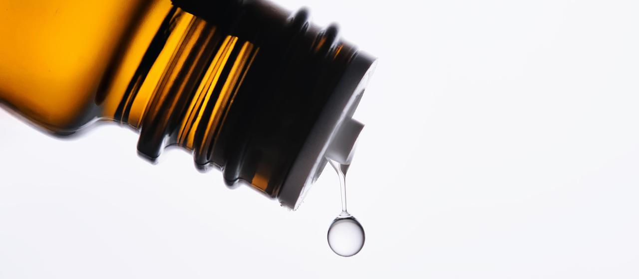 Ein Tropfen fällt aus einer Medikamentenflasche.