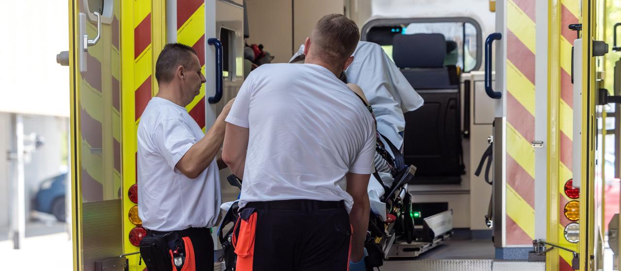 Rettungssanitäter kümmern sich um eine Patientin mit hitzebedingten Beschwerden.