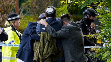 Mitglieder der jüdischen Gemeinde trösten sich gegenseitig in der Nähe der Synagoge der Heaton Park Hebrew Congregation in Crumpsall (Manchester).