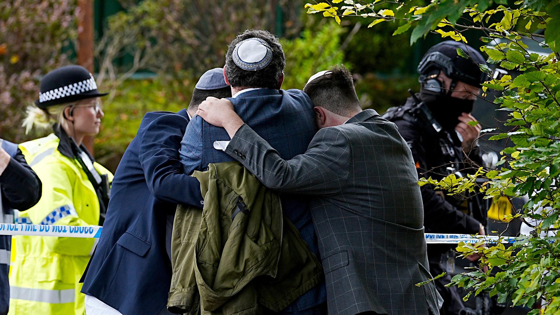 Mitglieder der jüdischen Gemeinde trösten sich gegenseitig in der Nähe der Synagoge der Heaton Park Hebrew Congregation in Crumpsall (Manchester). | AP
