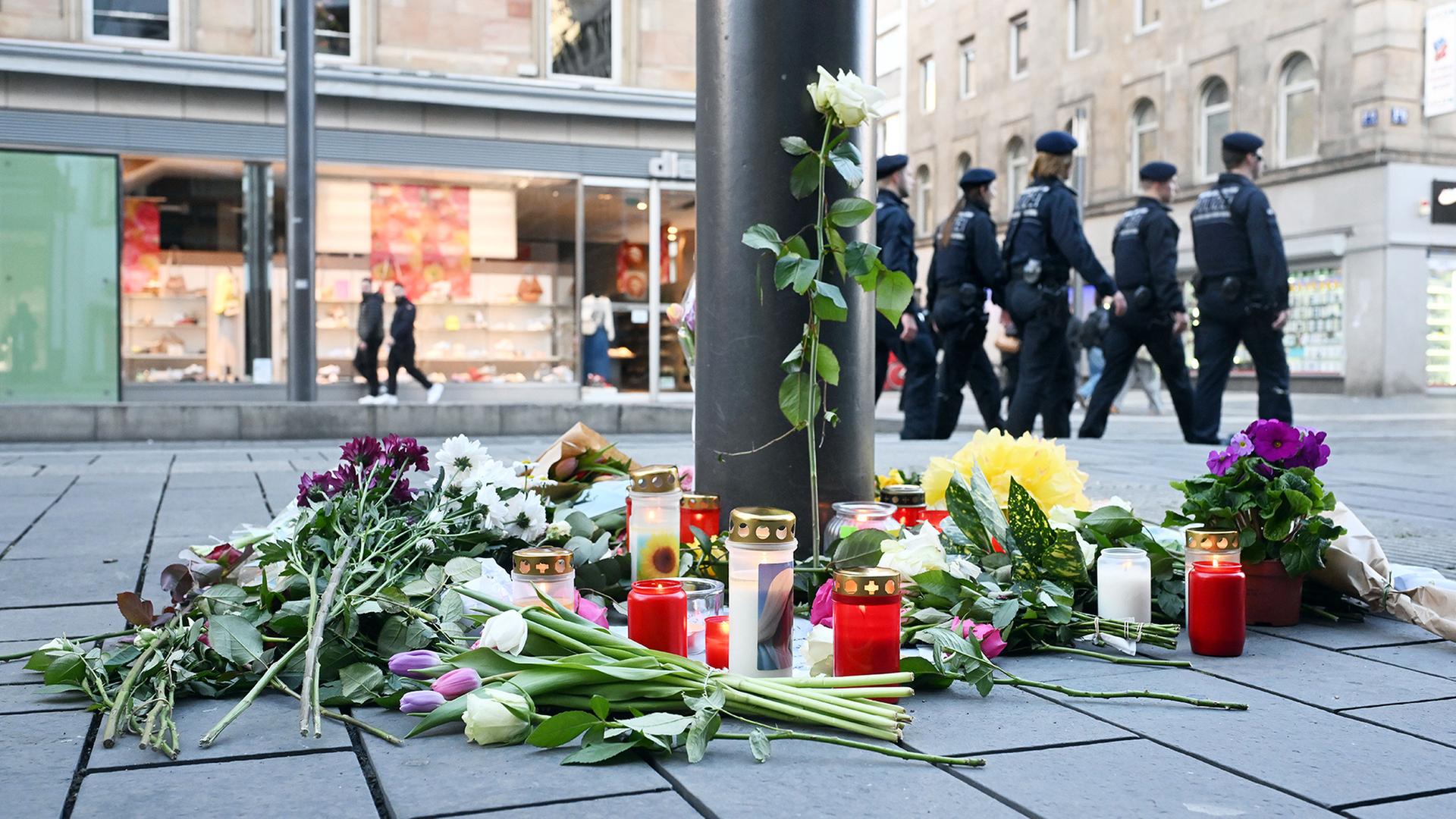 Kerzen und Blumen liegen in der Nähe des Paradeplatzes in Mannheim. | dpa