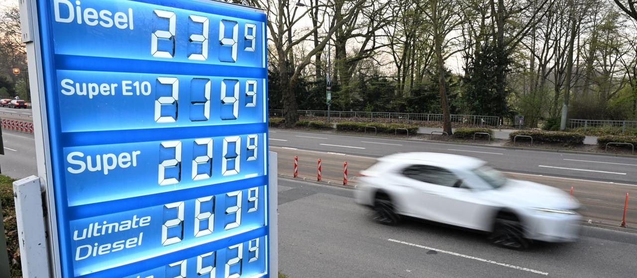 Ein Auto fährt an der Preisanzeige einer Tankstelle vorbei. 