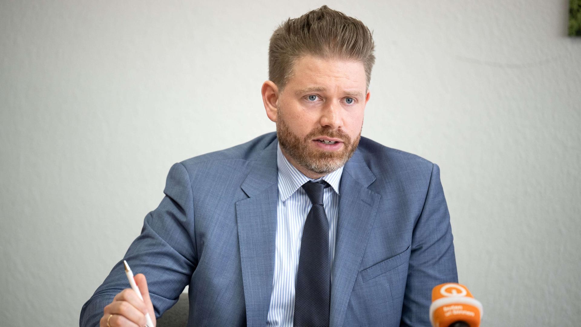 Thorge Koehler sitzt in Anzug an einem Tisch und spricht in einen butenunbinnen-Mikrofon | DPA | Sina Schuldt