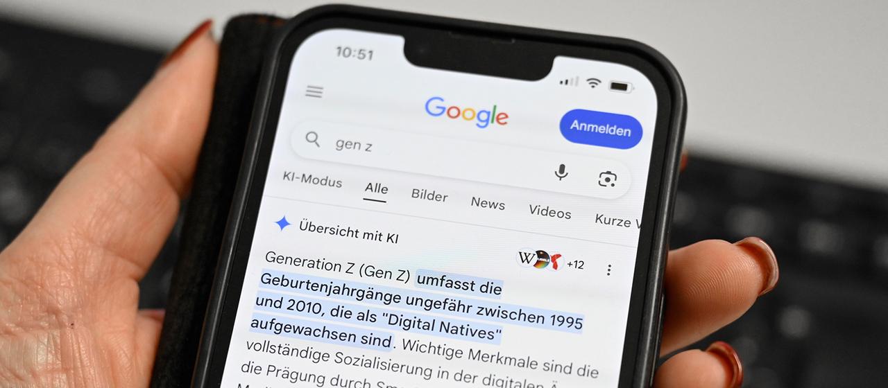 Auf dem Display eines Smartphones ist die Google-KI-Übersicht zu sehen.