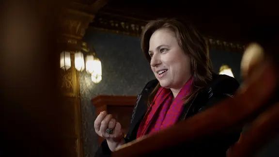 Judit Polgar lächelt mit einem pinken Schal um den Hals