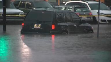 Ein dunkler Pkw steht bis zur Hälfte im Hochwasser.