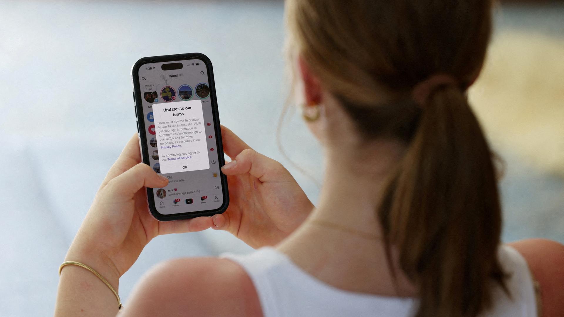 Eine Jugendliche blickt auf ihr Handy. | REUTERS