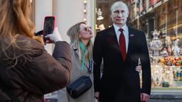 Eine junge Frau lässt sich fotografieren, während sie einen Pappaufsteller Wladimir Putins küsst.