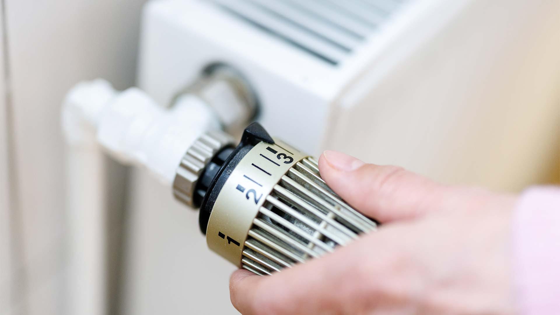 Eine Frau stellt an einem Thermostaten die Temperatur von einem Heizkörper ein. | picture alliance / dpa