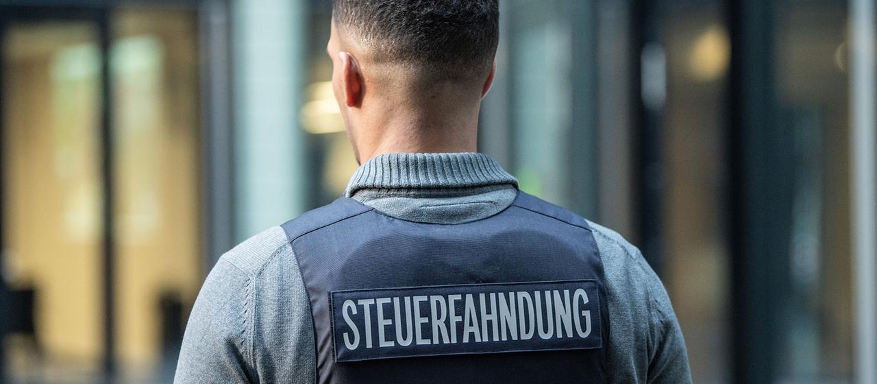 Ein Bediensteter der Steuerfahndung eine Schutzweste mit der Aufschrift "Steuerfahndung". 