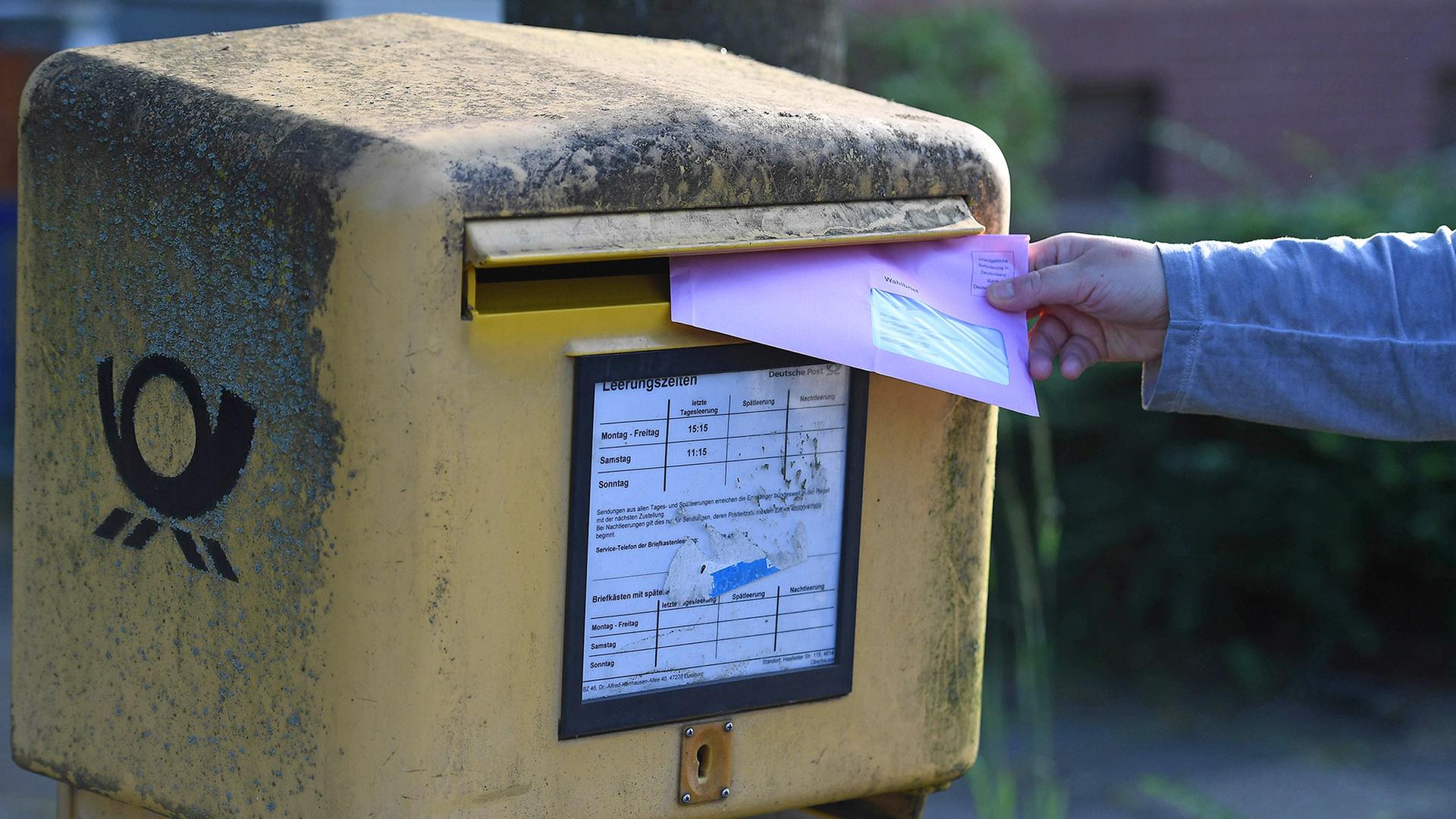 Symbolbild:Eine Person steckt einen Wahlbrief in einen Postkasten.(Quelle:picture alliance/Revierfoto) | picture alliance/Revierfoto