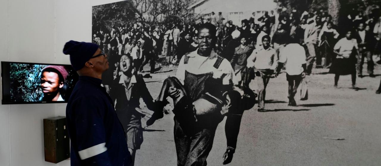 Ein Mann betrachtet ein Bild des Soweto-Aufstands.