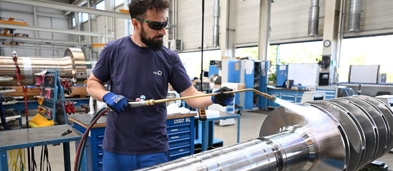 Ein KSB-Mitarbeiter bearbeitet mit einem Brenner ein Bauteil für eine Großpumpe.