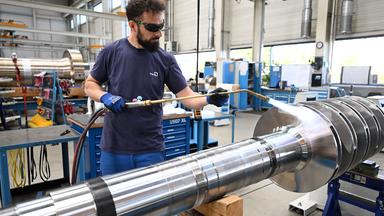 Ein KSB-Mitarbeiter bearbeitet mit einem Brenner ein Bauteil für eine Großpumpe.