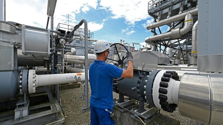 Ein Arbeiter dreht im Gasspeicher Haidach, Österrecich,  an einem Handrad einer Leitung.