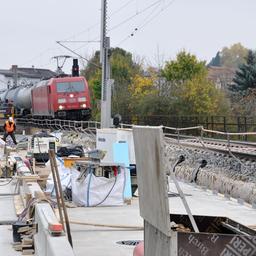 Ein Güterzug auf einer Brückenbaustelle der Saalebahn