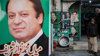 Ein Mann steht neben Wahlplakaten von Nawaz Sharif