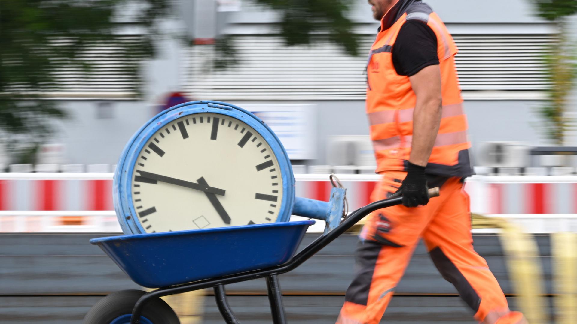  Ein Arbeiter transportiert eine Uhr auf einer Schubkarre | Arne Dedert/dpa