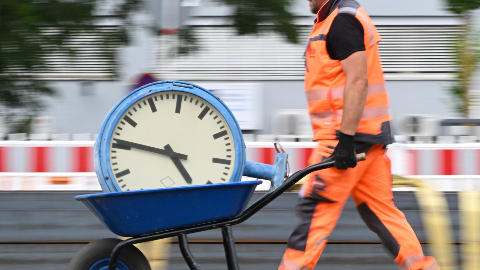  Ein Arbeiter transportiert eine Uhr auf einer Schubkarre | Arne Dedert/dpa