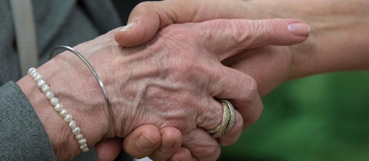 Hand einer alten und einer jüngeren Person.