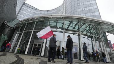 Personen mit polnischer Flagge vor dem Hauptsitz des staatlichen polnischen Fernsehsenders TVP