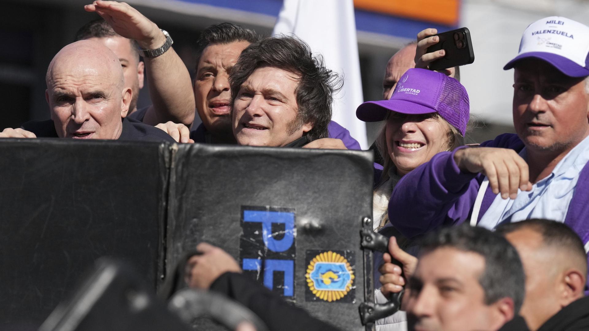 Argentiniens Präsident Javier Milei wird gegen herbeifliegende Steine von der Polizei abgeschirmt. | AP