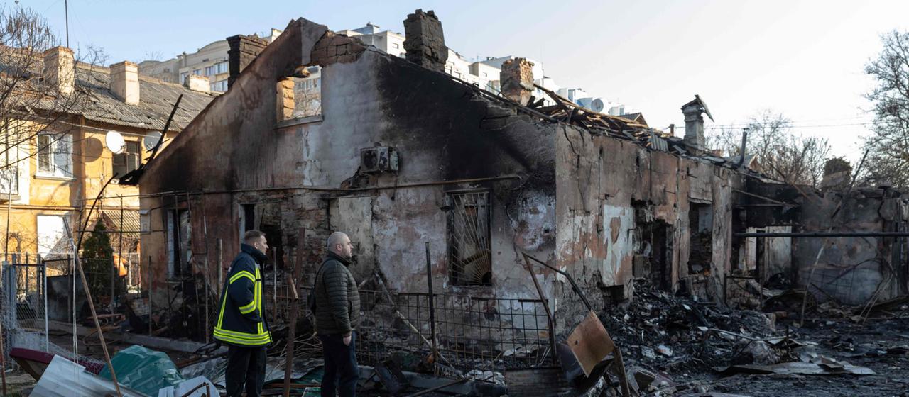 Zwei Männer stehen inmitten zerstörter Gebäude in der ukrainischen Stadt Odessa. 