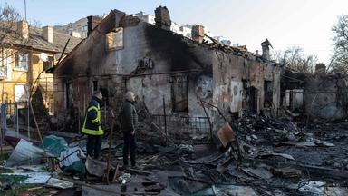 Zwei Männer stehen inmitten zerstörter Gebäude in der ukrainischen Stadt Odessa. 