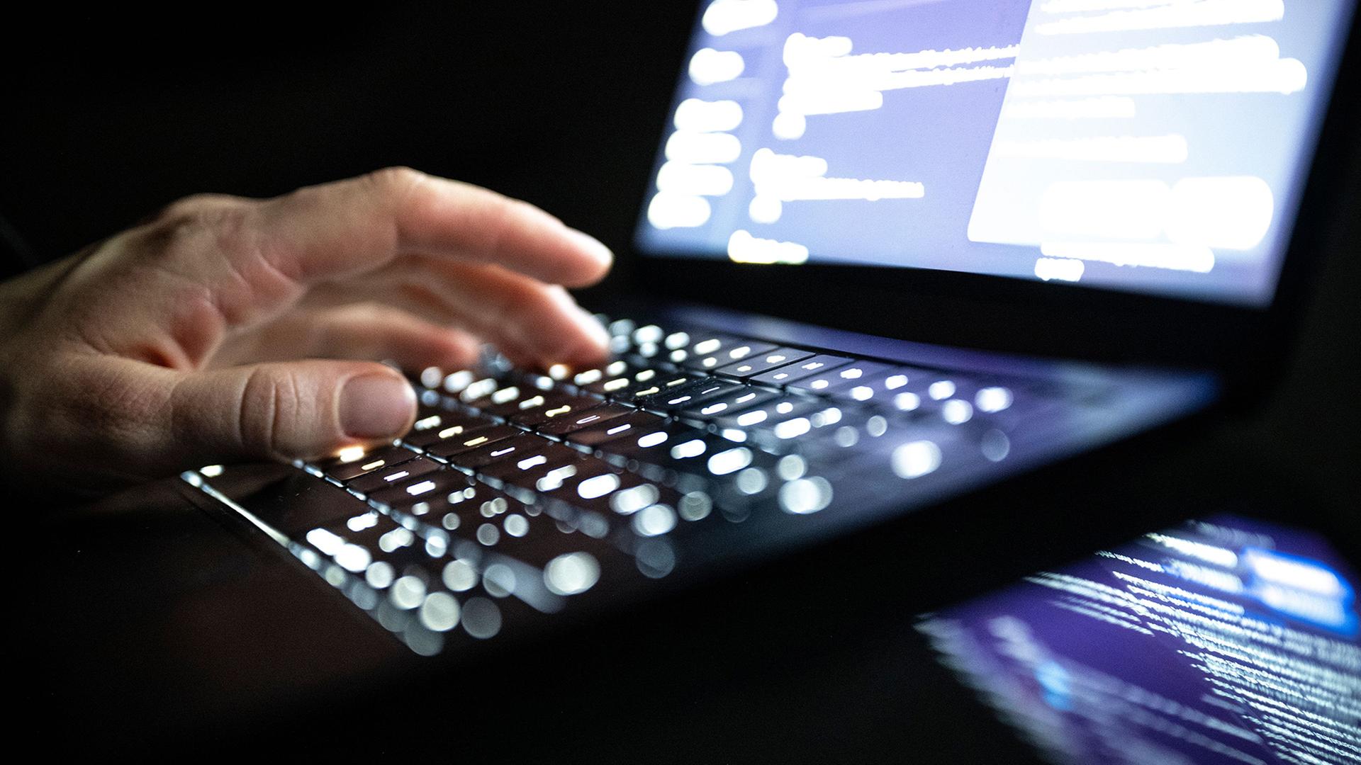 Eine Person tippt mit den Fingern auf einer beleuchteten Laptop-Tastatur. | Philip Dulian/dpa