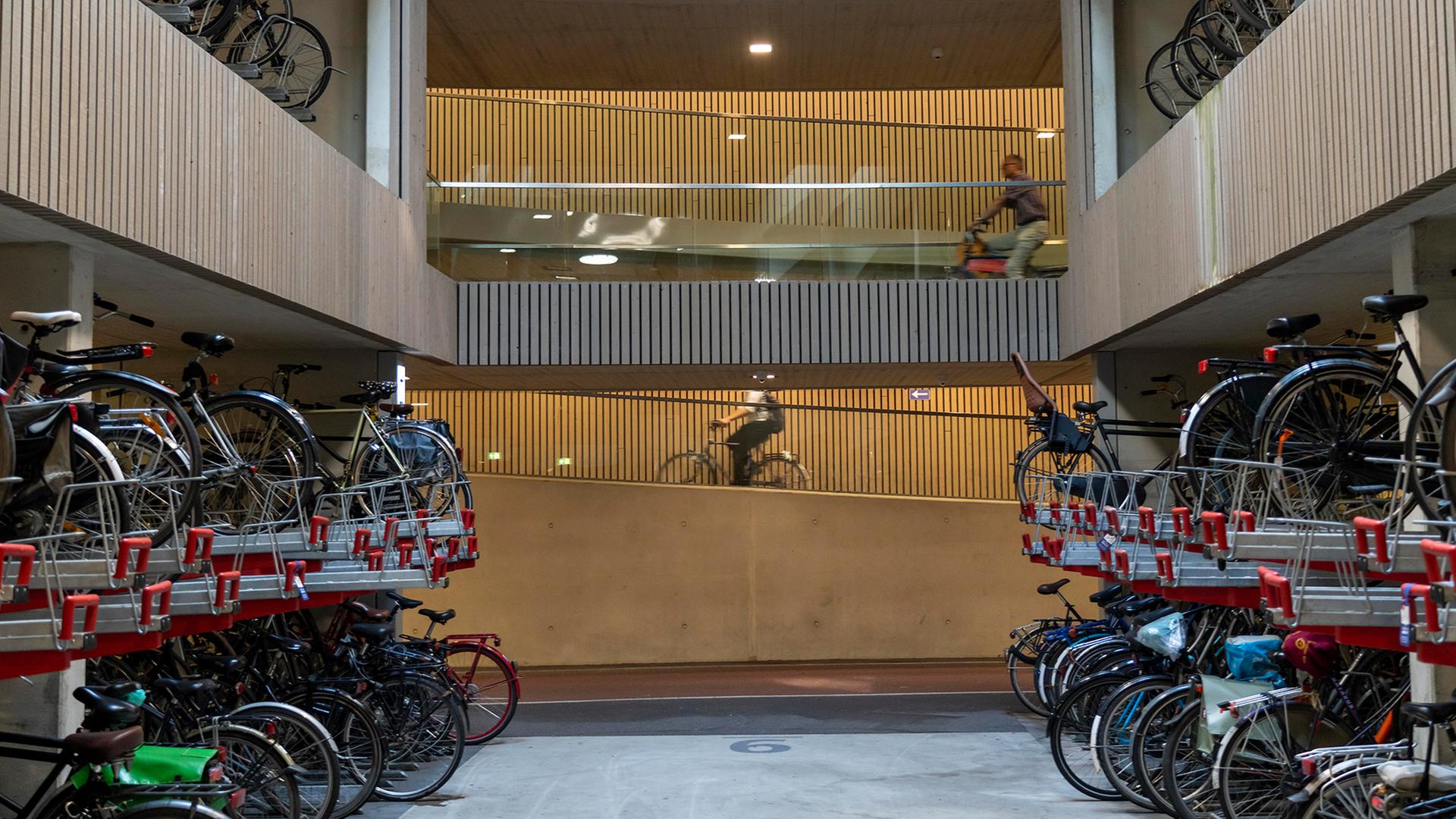Personen fahren durch eine Parkhaus für Fahrräder. (Archivbild: 13.6.2025) | picture alliance / Jochen Tack
